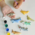 Children painting small animal figurines on a white surface
