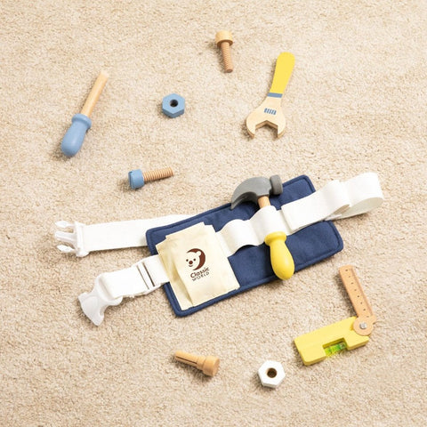 A Classic World Tool Belt from Classic World rests on a beige carpet, ready to inspire imaginative play. This set features a white belt with a blue pouch that holds a hammer. Scattered around the belt are various children's carpentry tools, including a toy wrench, ruler, screws, nuts, and bolts in coordinating shades of blue, yellow, and natural wood.