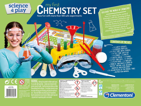 A vibrant packaging for the "Clementoni Science & Play - LAB My First Chemistry Set" by Clementoni. The kit features safety goggles, test tubes, pipettes, a funnel, a spatula, and other contemporary scientific tools. A young girl sporting safety goggles is pictured on the left. Text on the box emphasizes fun and safe chemistry experiments in a modern chemistry laboratory setting.