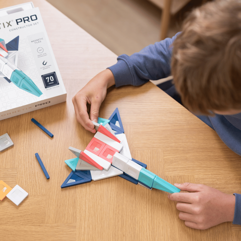 Child playing with a construction set on a table next to a Pro Construction Set box.