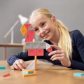 Young girl playing with colorful building blocks on a wooden table.