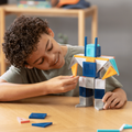 Child playing with a colorful building block robot on a wooden table.