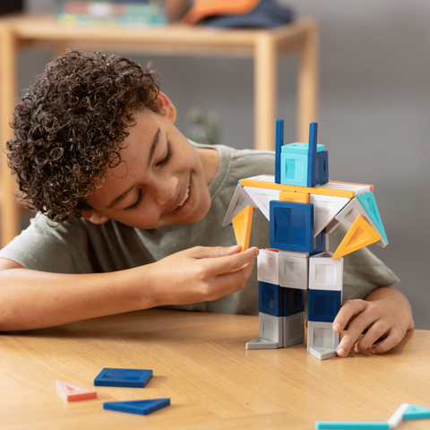 Child playing with a colorful building block robot on a wooden table.