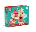 The image shows a HAPE Tea Set in its original packaging. This enchanting tea set is suitable for children aged 2-8 years and includes a wooden teapot, cups, snacks, and accessories in vibrant colors. The box features illustrations of the contents and product details.