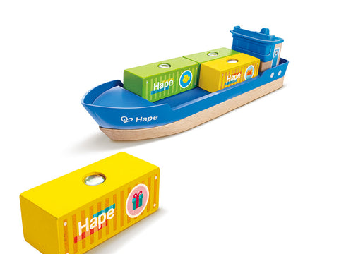 The Hape Cargo Ship & Crane is a wooden toy ship with a blue and natural wood color scheme. It includes three colorful cargo blocks—one yellow, one green, and one blue—each marked "Hape." Additionally, a yellow cargo block featuring a gift symbol is positioned separately in the foreground, making it perfect for pairing with Hape railway sets.