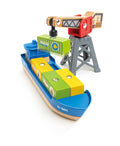 Introducing the Hape Cargo Ship & Crane: a vibrant toy cargo ship loaded with yellow, green, and blue blocks. A magnetic crane with a striking red and gray design lifts a green block featuring a fruit image. The ship, marked "H-001" on its blue exterior, perfectly complements Hape railway sets.