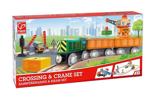 A "Hape Crossing & Crane Set" package showcasing a green and orange train, a magnetic crane, rail tracks, and a level crossing. The box is labeled with the "Hape" brand name and features an illustration of the set in use. Suitable for ages 3 and up, it also includes various rail track accessories for enhanced fun.