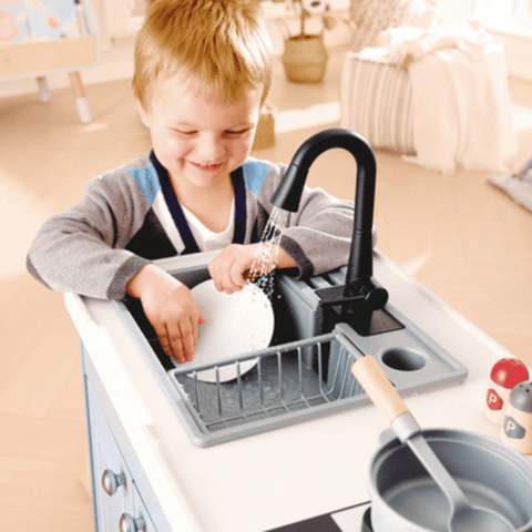 Cihld playing with the Hape Deluxe Kitchen with Running Water 