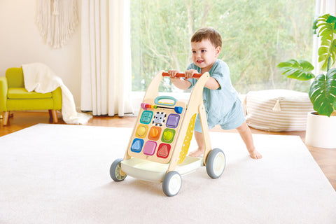 Child taking first steps with the Hape Grow-With-Me Push Walker