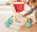 Child playing with a Hape Little Shopper's Cart & Basket on a light wood floor.