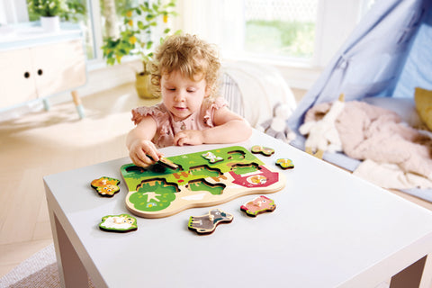 Close-up of the Hape Farm Animals Peg Puzzle wooden pieces, each with a chunky peg designed for small hands.
