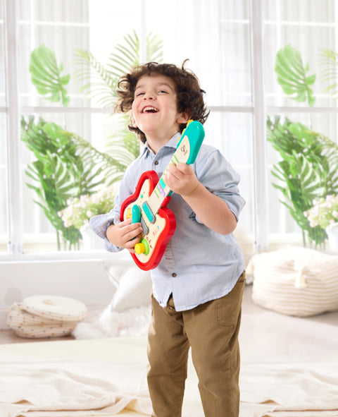 Child playing the Hape Pixelz Rainbow Rock Guitar