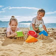 Two children playing in the sand with Hape Sand toys at the beach.