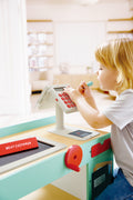 Child playing with a Hape Smart Play Shop at a children's play area.