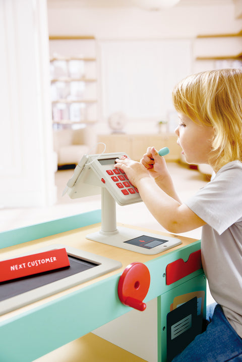 Child playing with a Hape Smart Play Shop at a children's play area.