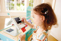 Child playing with a Hape Smart Play Shop at a table