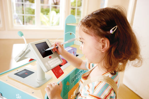 Child playing with a Hape Smart Play Shop at a table