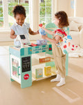 Two children playing with a Hape Smart Play Shopset in a living room.