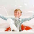 Child in a bathtub filled with bubbles and water, enjoying a bath.