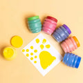 Colorful paint pots with a yellow paw print template on a beige background