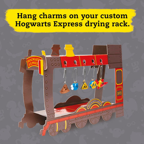 The Klutz Harry Potter Clay Charms drying rack, designed as a cardboard model of the Hogwarts Express train, is perfect for hanging your charm jewelry. Featuring whimsical charms such as a pie, a yellow shape, and a potion bottle made from polymer clay, this rack captures the enchantment of the Harry Potter series. The text at the top encouragingly states, "Hang charms on your custom Hogwarts Express drying rack.