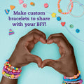 Two hands, adorned with colorful beaded bracelets, form a heart shape against a light blue background. Various bracelet-making beads and tools from "Klutz The Ultimate Clay Bead Book" by KLUTZ surround the text "Make custom bracelets to share with your BFF!" in purple font.