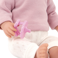 Close-up of a Lullababy doll wearing a pink sweater and white pants, holding a pink toy.