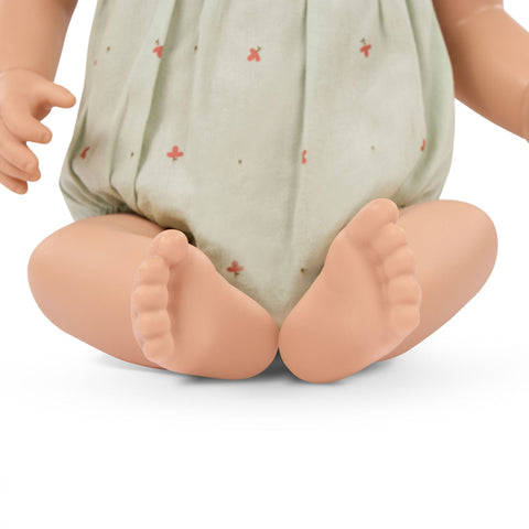 Close-up of a Lullababy doll's feet wearing a light green outfit with small red patterns on a white background