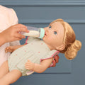 Child feeding a Lullababy doll with a bottle against a blue background