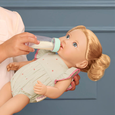 Child feeding a Lullababy doll with a bottle against a blue background
