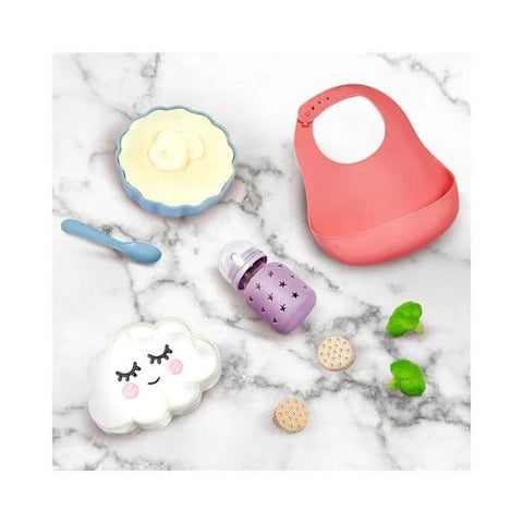 Baby utensils including a bib, spoon, and bottle on a marble surface