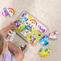 Overhead view of a child playing with the Melissa & Doug Unicorn Chunky Puzzle, placing pieces into the castle and meadow board
