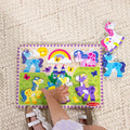 Overhead view of a child's hand placing pieces into the Melissa & Doug Unicorn Chunky Puzzle, with the pink and blue unicorn pieces lifted out to the side