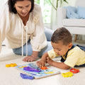 A parent and toddler playing with the Melissa & Doug Sea Life Chunky Puzzle on the floor, with several sea creature pieces scattered around the board