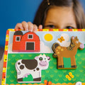 Close-up of a child holding the Melissa & Doug Chunky Farm Puzzle, showing the barn, cow and horse pieces up close