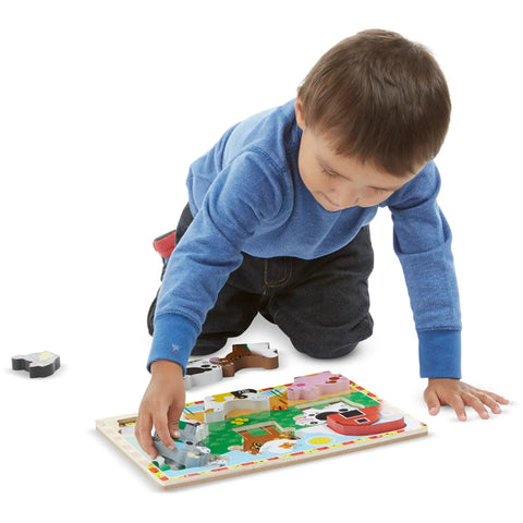 Child kneeling on the floor assembling the Melissa & Doug Chunky Farm Puzzle, placing the animal pieces into the board