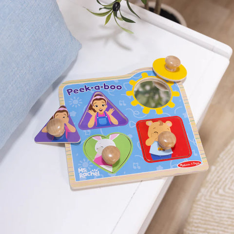 Children's wooden peek-a-boo toy with cartoon characters on a white surface.