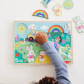 Child playing with a colorful wooden puzzle featuring animals and a rainbow.