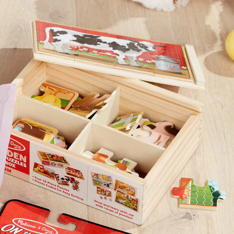 Open Melissa & Doug Farm Puzzles wooden storage box showing the four puzzle compartments with pieces sorted inside, and the slide-on lid used as a puzzle board