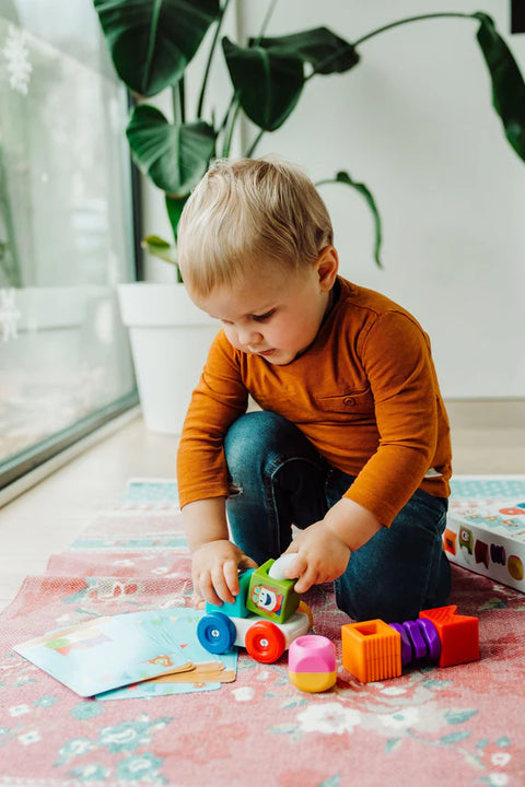 Child sitting on the floor playing with the SmartMax My First Build & Drive Set