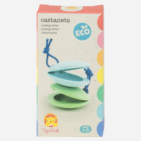 A box of eco-friendly TIGER TRIBE Castanets, designed as an educational musical tool for children aged 1-5, includes pastel green and blue castanets tied with a blue cord. The bio plastic packaging features text in multiple languages and showcases a playful lion character from Tiger Tribe.