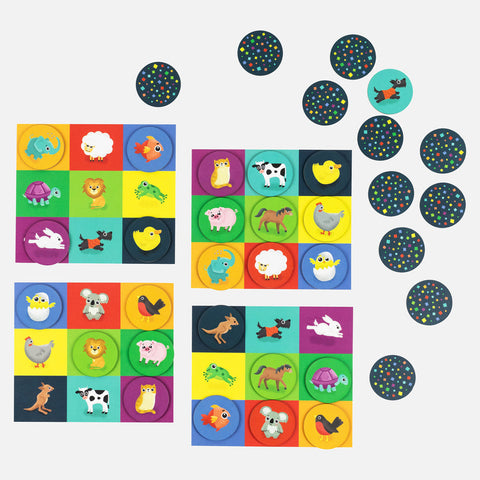 Four sets of vibrant cards showcasing illustrations of different animals including elephants, sheep, fish, and cows. Nearby, circular tokens adorned with multicolored dots on a black background are scattered. Created by TIGER TRIBE for Tiger Tribe Memory + Bingo - Animals, this game enhances cognitive abilities through engaging memory challenges.