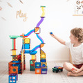 A child dropping a ball into a tall TileTek Ball Run tower built in a playroom