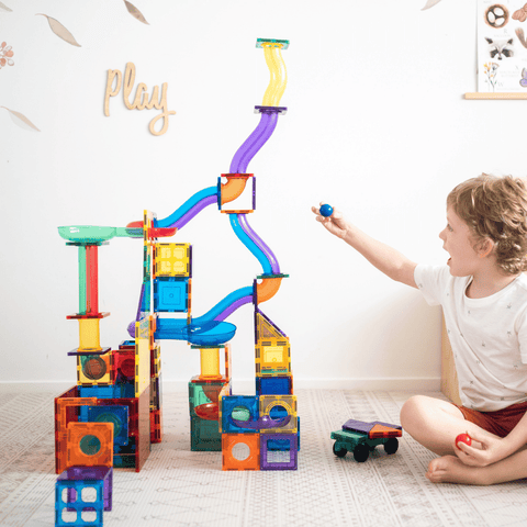 A child dropping a ball into a tall TileTek Ball Run tower built in a playroom
