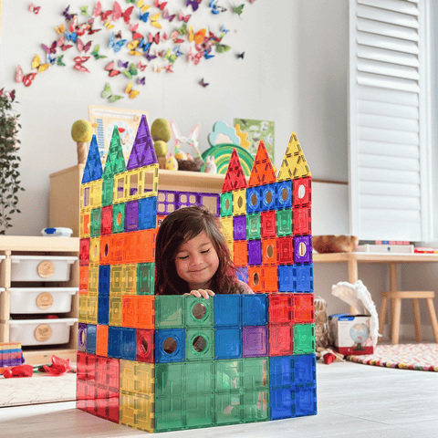Child standing inside a large TileTek magnetic tile castle built tall enough to climb into
