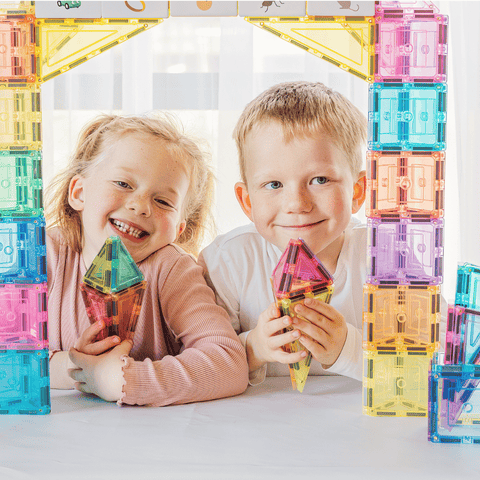 Two children smiling behind a doorway built from pastel TileTek magnetic tiles
