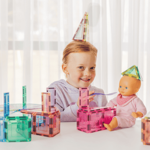 Child wearing a pastel TileTek triangle tile as a party hat beside a doll