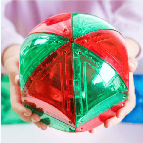 Child holding a red and green TileTek magnetic tile dome sphere