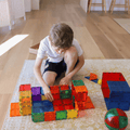 Child kneeling on a rug building a colourful TileTek magnetic tile structure