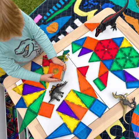 Child arranging TileTek magnetic tile triangles into a mosaic pattern outdoors